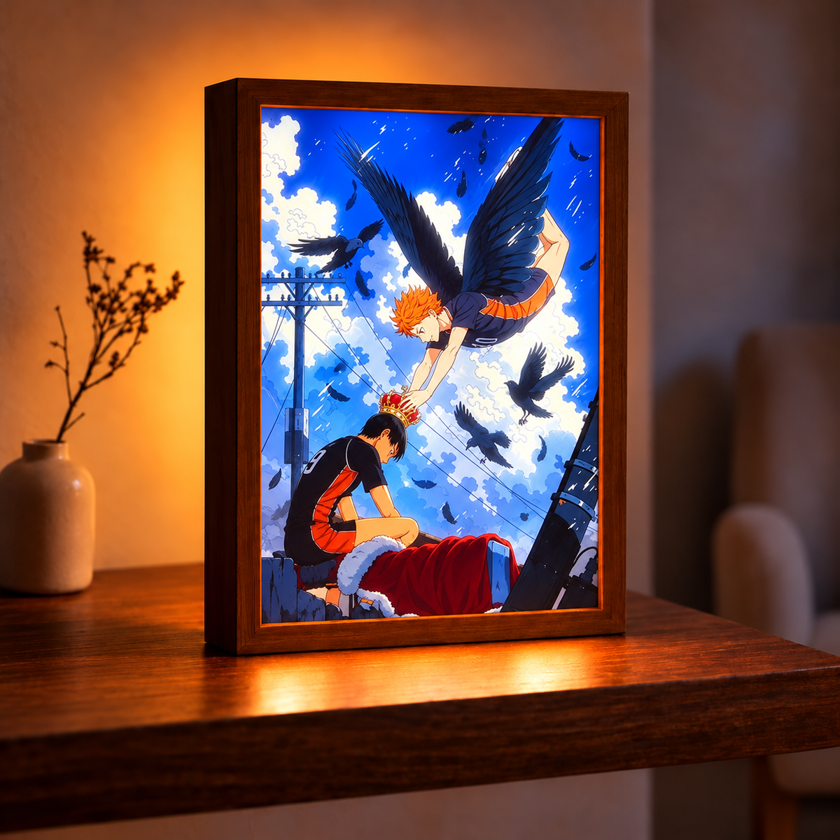 Haikyuu Crowning Flight illuminated artwork in a wood-tone frame on a wooden table, glowing with a blue sky, black wings, and a red-and-gold crown